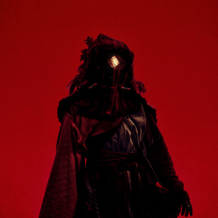 Album cover for 'Sanctuary', by Levitation Orchestra. A figure stands before a red background. The figure looks kind of scary, dressed in all black leather, a crimson cloak, an almost crow-like helmet with a single golden diamond-shaped 'eye' in the centre.