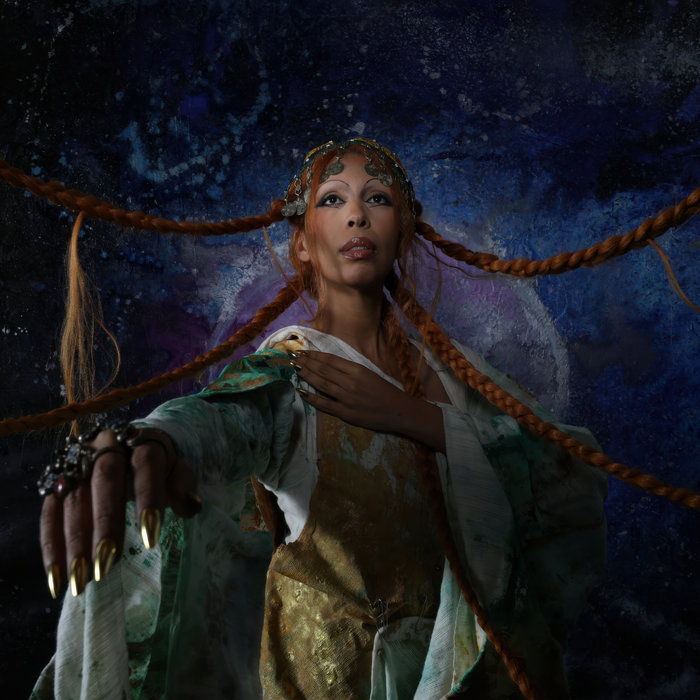 Album cover for 'The Prophet and The Madman' by Ami Taf Ra. Ami is dressed in white and gold robes, with 5 long ginger braids in her hair. Her right hand reaches towards the viewer as she looks up, and the braids extend away from her head and body as if held on strings.